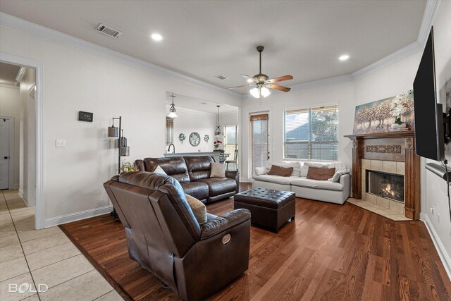 living room with ornamental molding, a fireplace, visible vents, and baseboards