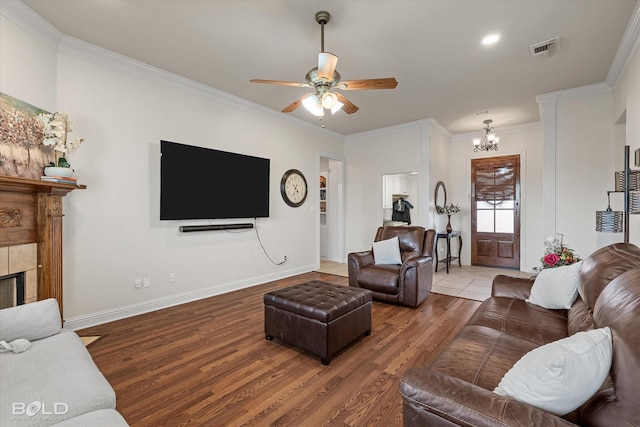 living room with crown molding, a fireplace, visible vents, and wood finished floors