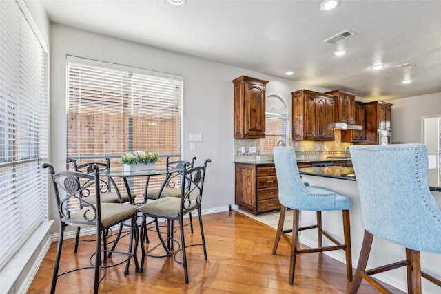 kitchen with tasteful backsplash, visible vents, a breakfast bar, light wood-type flooring, and recessed lighting