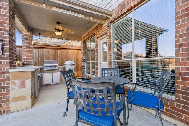 view of patio / terrace with grilling area, fence, exterior kitchen, outdoor dining area, and a ceiling fan