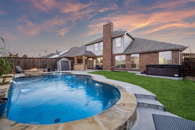 view of pool featuring a hot tub, a storage shed, a yard, a fenced backyard, and an outdoor structure