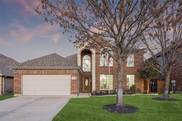 view of front facade featuring brick siding, a garage, a shingled roof, and a front lawn