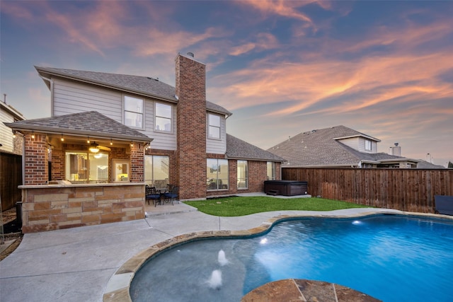 pool at dusk featuring outdoor dry bar, a fenced in pool, a hot tub, a fenced backyard, and a patio