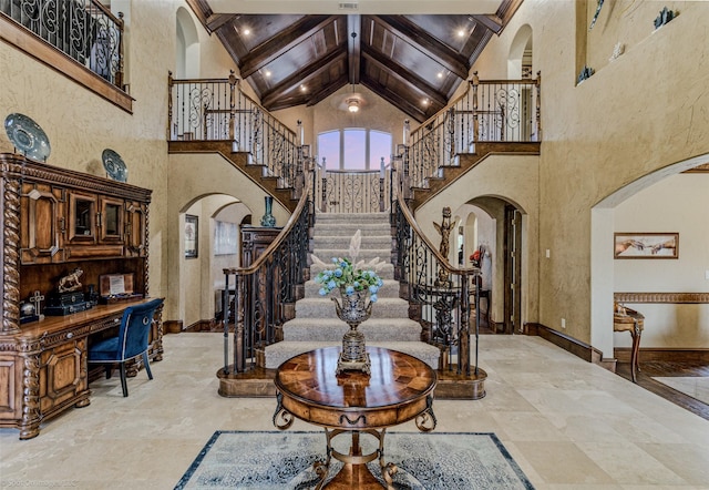 foyer with high vaulted ceiling, arched walkways, beam ceiling, and baseboards