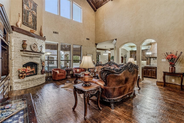 living area featuring arched walkways, a fireplace, wood-type flooring, and visible vents