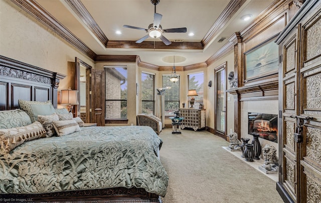 bedroom featuring visible vents, light colored carpet, a fireplace with flush hearth, ornamental molding, and a tray ceiling