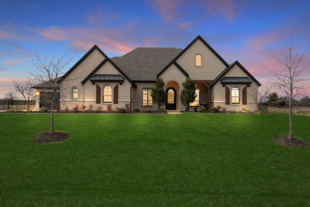 french country style house with brick siding, a front lawn, and roof with shingles