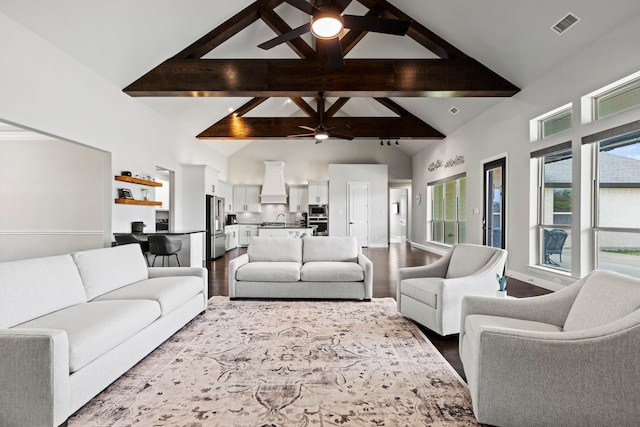 living room with ceiling fan, high vaulted ceiling, visible vents, dark wood-style floors, and beamed ceiling