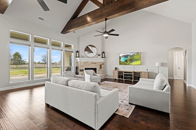 living area with arched walkways, a ceiling fan, dark wood-style floors, a fireplace, and high vaulted ceiling