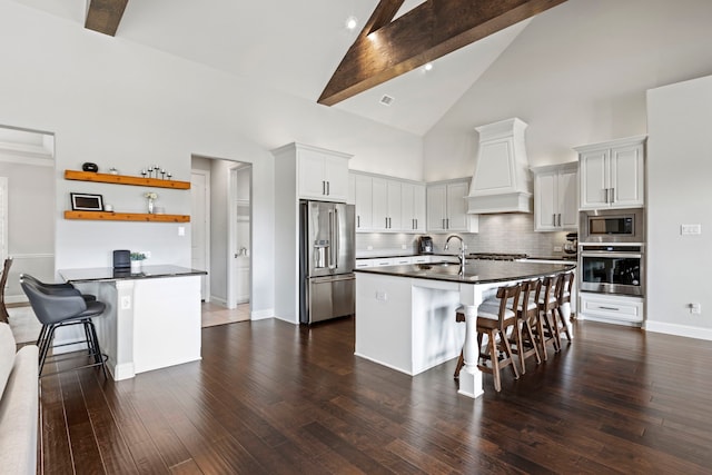 kitchen with appliances with stainless steel finishes, a breakfast bar, premium range hood, and dark countertops