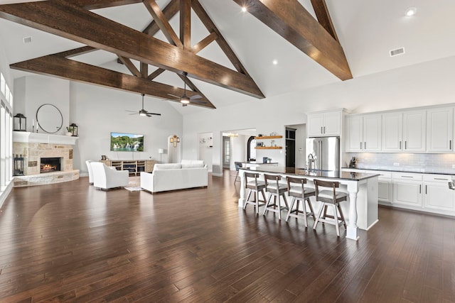 kitchen featuring visible vents, a kitchen breakfast bar, open floor plan, a fireplace, and high end fridge