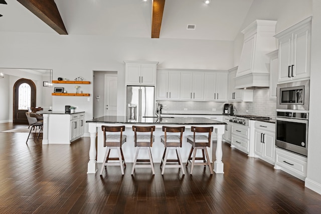 kitchen featuring dark countertops, visible vents, a kitchen bar, and appliances with stainless steel finishes