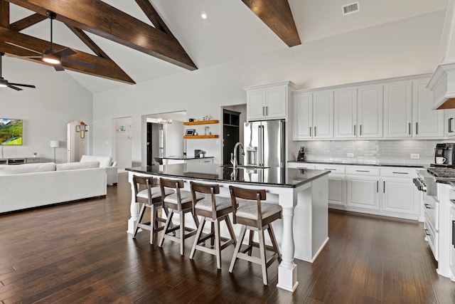 kitchen featuring visible vents, a kitchen breakfast bar, a ceiling fan, high end appliances, and dark countertops