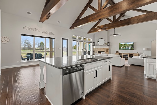 kitchen with dark wood-style floors, stainless steel dishwasher, open floor plan, a sink, and a stone fireplace