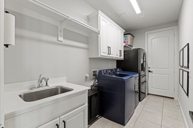 laundry area featuring light tile patterned floors, washing machine and clothes dryer, a sink, and cabinet space