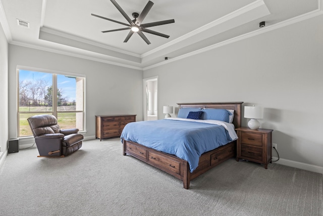 carpeted bedroom with visible vents, a tray ceiling, baseboards, and ornamental molding