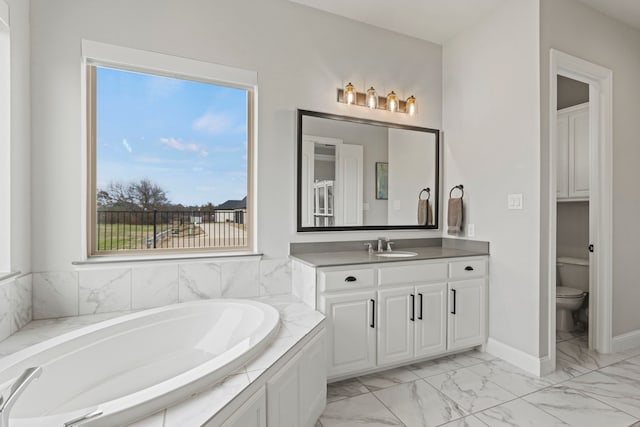 full bath featuring marble finish floor, a garden tub, toilet, vanity, and baseboards