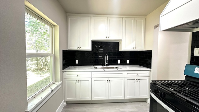 kitchen featuring stainless steel gas range oven, a sink, light stone counters, and decorative backsplash