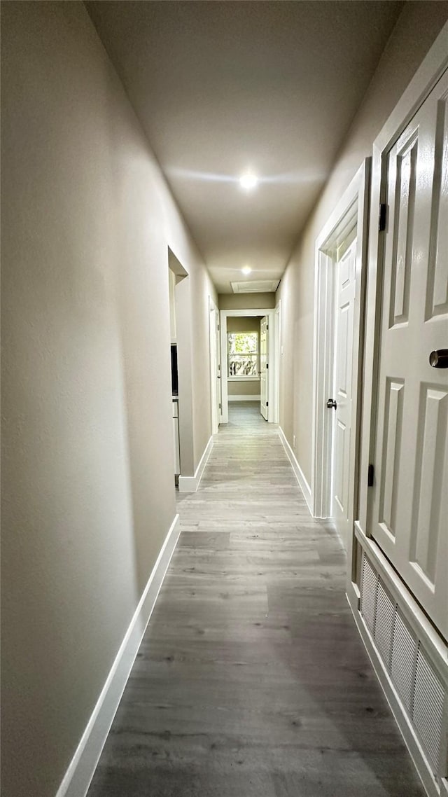 hallway featuring visible vents, baseboards, and wood finished floors