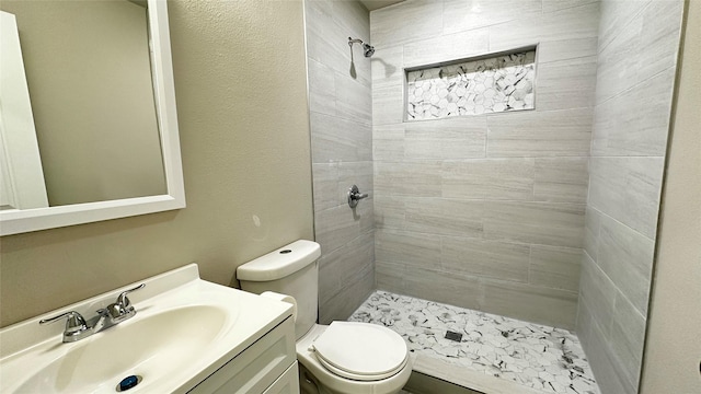 full bathroom featuring a stall shower, a textured wall, vanity, and toilet