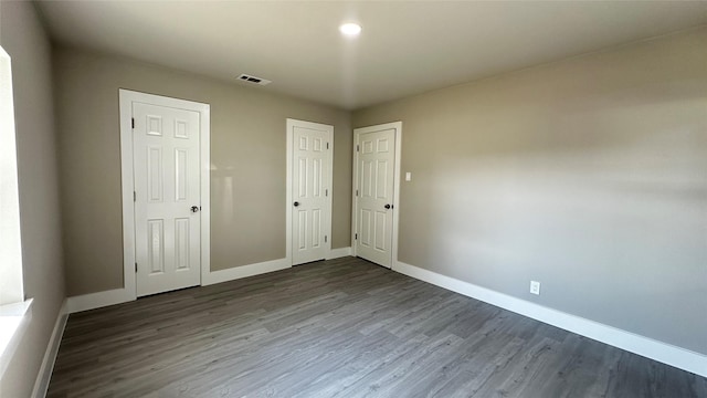 unfurnished bedroom featuring a closet, visible vents, baseboards, and wood finished floors