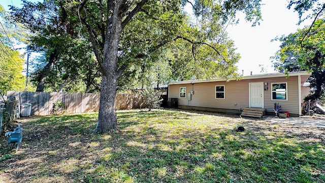 view of yard featuring entry steps, fence, and central air condition unit