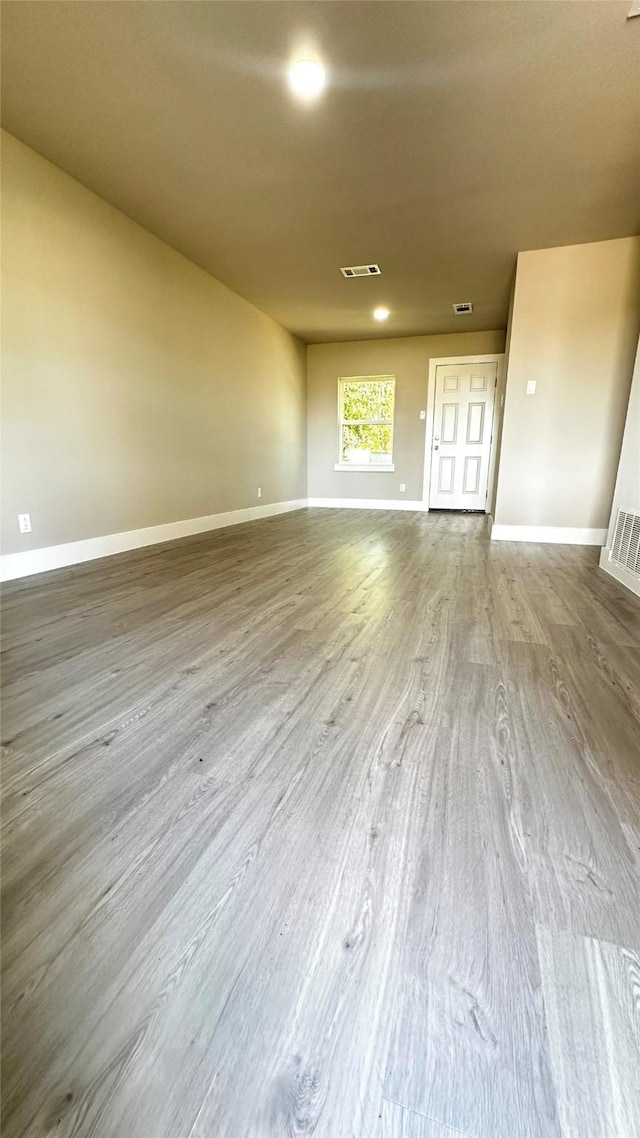 spare room with visible vents, baseboards, and wood finished floors