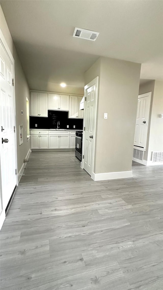 kitchen with stove, a sink, visible vents, and white cabinets