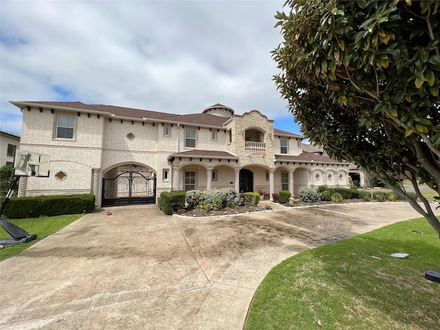 mediterranean / spanish home featuring driveway, a front yard, and a gate