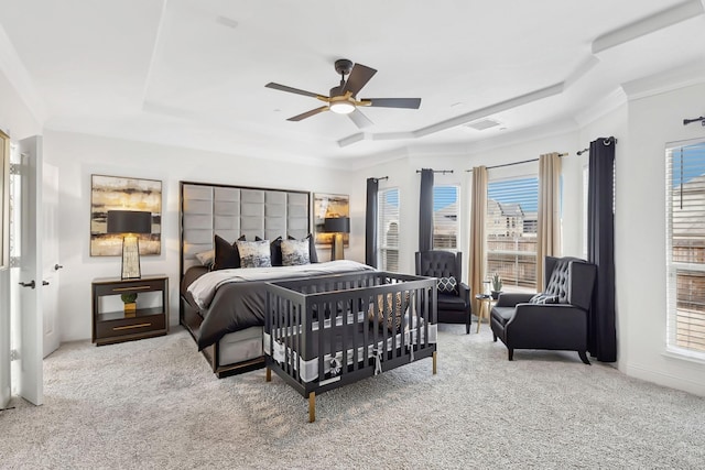 carpeted bedroom with visible vents, a tray ceiling, and a ceiling fan