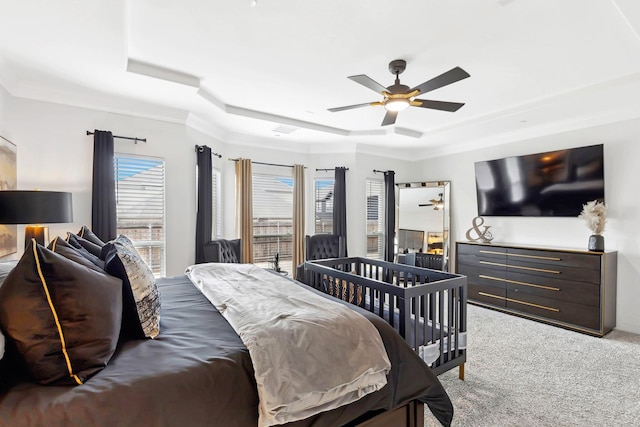 bedroom featuring a ceiling fan, a raised ceiling, light carpet, and crown molding