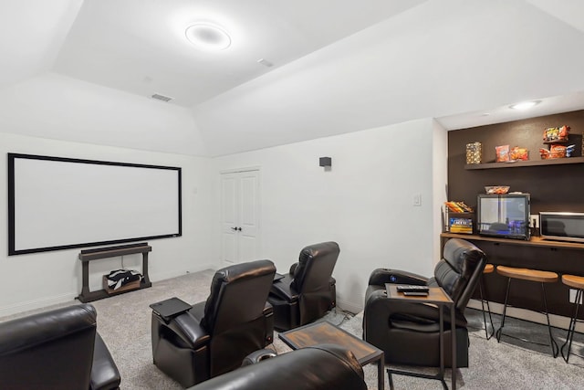 carpeted home theater room featuring vaulted ceiling, visible vents, and baseboards