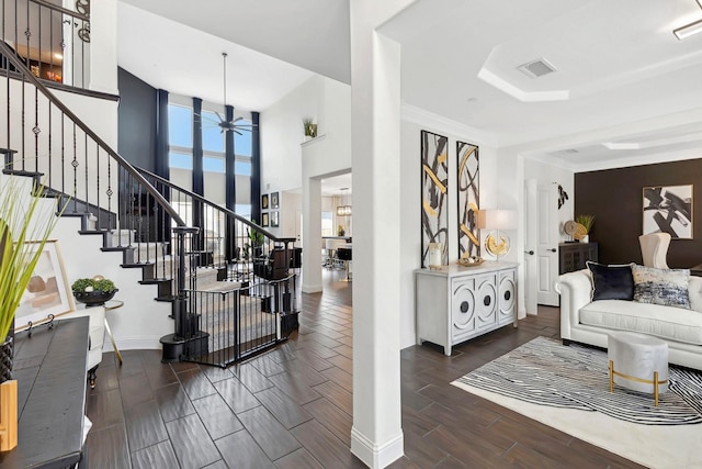 living room with wood finish floors, visible vents, ceiling fan, baseboards, and stairs