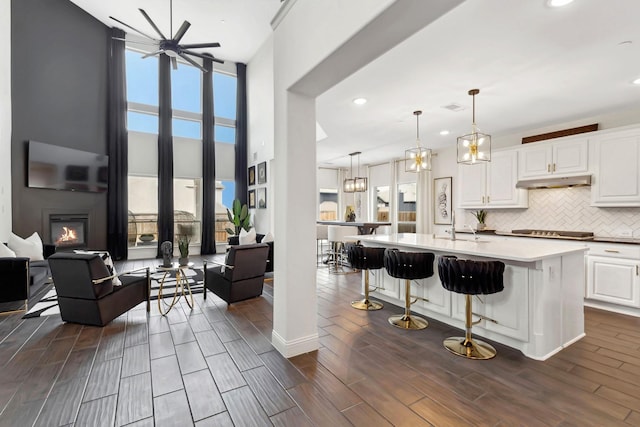 kitchen with a healthy amount of sunlight, wood tiled floor, white cabinetry, and decorative backsplash