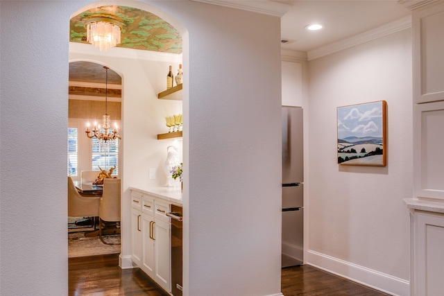 hallway with a notable chandelier, visible vents, baseboards, ornamental molding, and dark wood-style floors