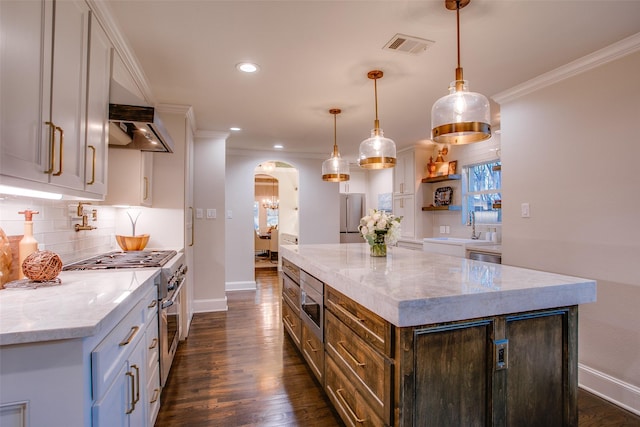 kitchen featuring visible vents, arched walkways, stainless steel appliances, crown molding, and backsplash