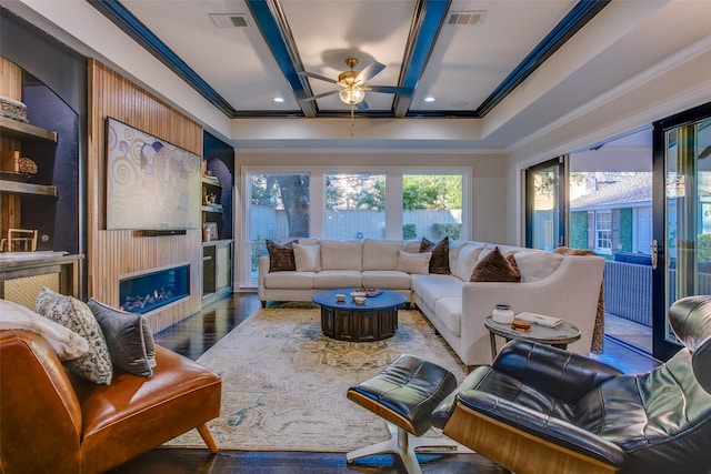 living room with wood finished floors, visible vents, and crown molding