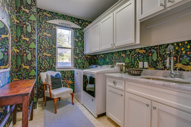 laundry area with cabinet space, wallpapered walls, washer and clothes dryer, and a sink