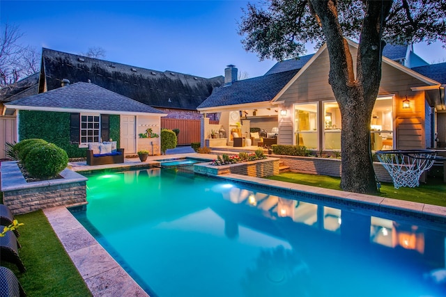 view of pool featuring an outbuilding, fence, a pool with connected hot tub, a patio area, and an exterior structure