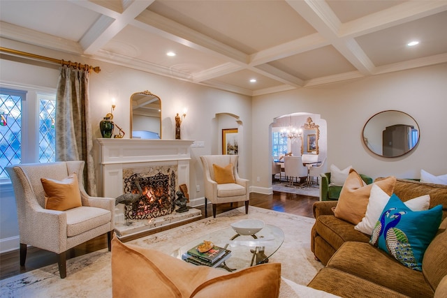 living area featuring arched walkways, coffered ceiling, a premium fireplace, wood finished floors, and beam ceiling