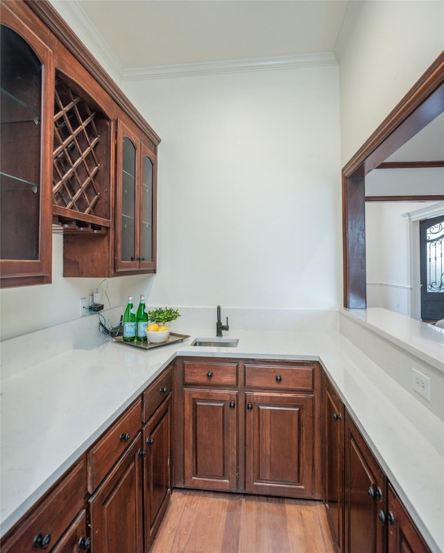 bar featuring a sink, light wood-style floors, and crown molding