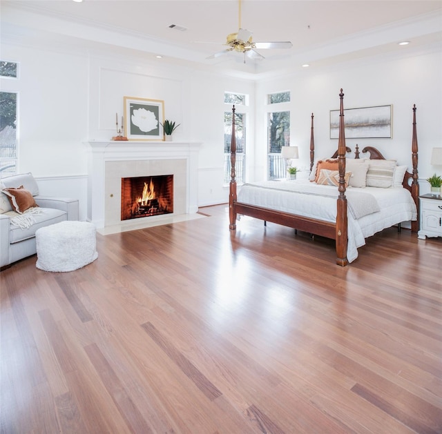 bedroom with wood finished floors, visible vents, recessed lighting, ceiling fan, and a tile fireplace