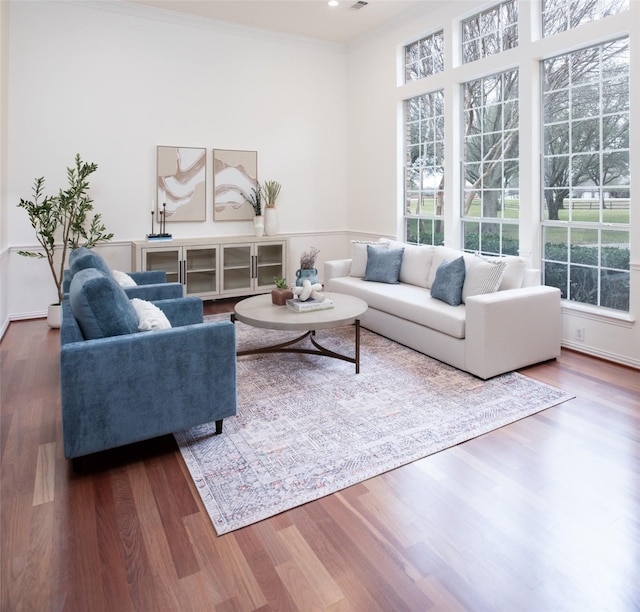 living area with visible vents, crown molding, and wood finished floors