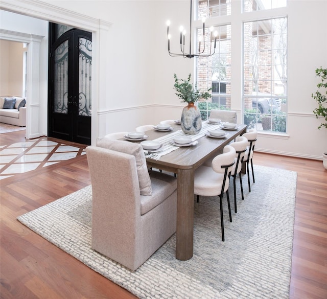 dining area featuring french doors, an inviting chandelier, and wood finished floors