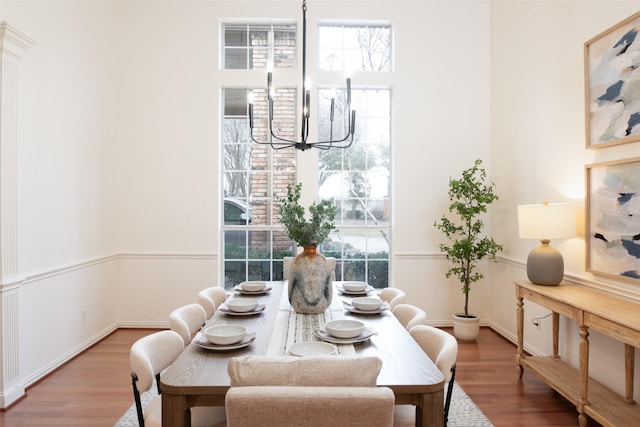 dining space with a wealth of natural light, an inviting chandelier, and wood finished floors