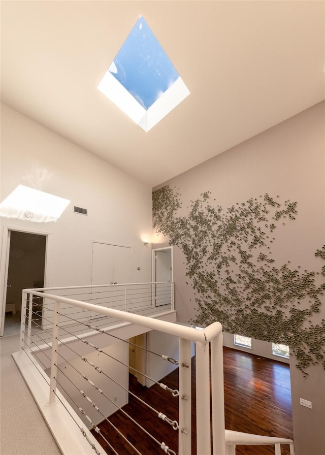 stairs featuring vaulted ceiling with skylight, visible vents, and wood finished floors