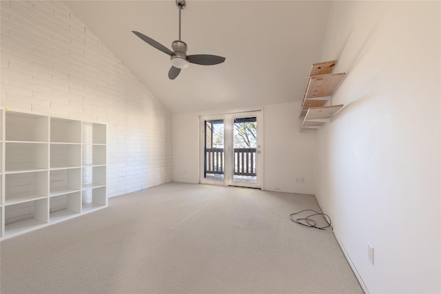 empty room featuring vaulted ceiling, brick wall, ceiling fan, and carpet