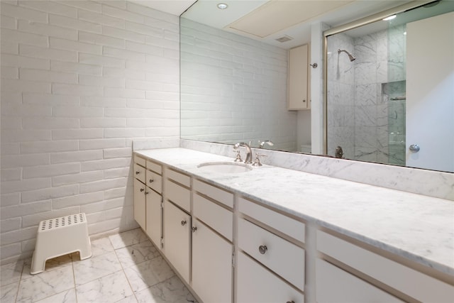 full bathroom with tile walls, marble finish floor, a shower stall, and vanity