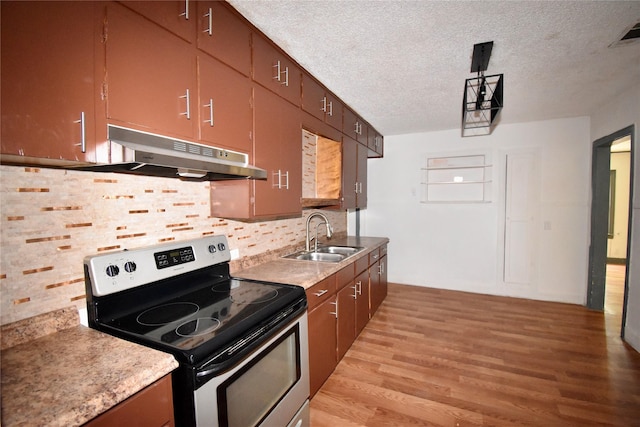 kitchen with a textured ceiling, light wood-style flooring, under cabinet range hood, a sink, and electric stove