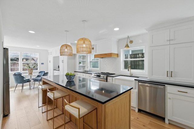 kitchen with premium range hood, light wood-type flooring, stainless steel appliances, dark countertops, and tasteful backsplash